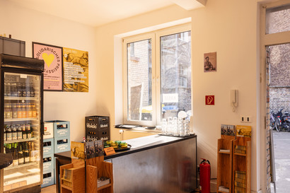 Bar von innen. Man sieht die Theke und einen gefüllten Getränkekühlschrank