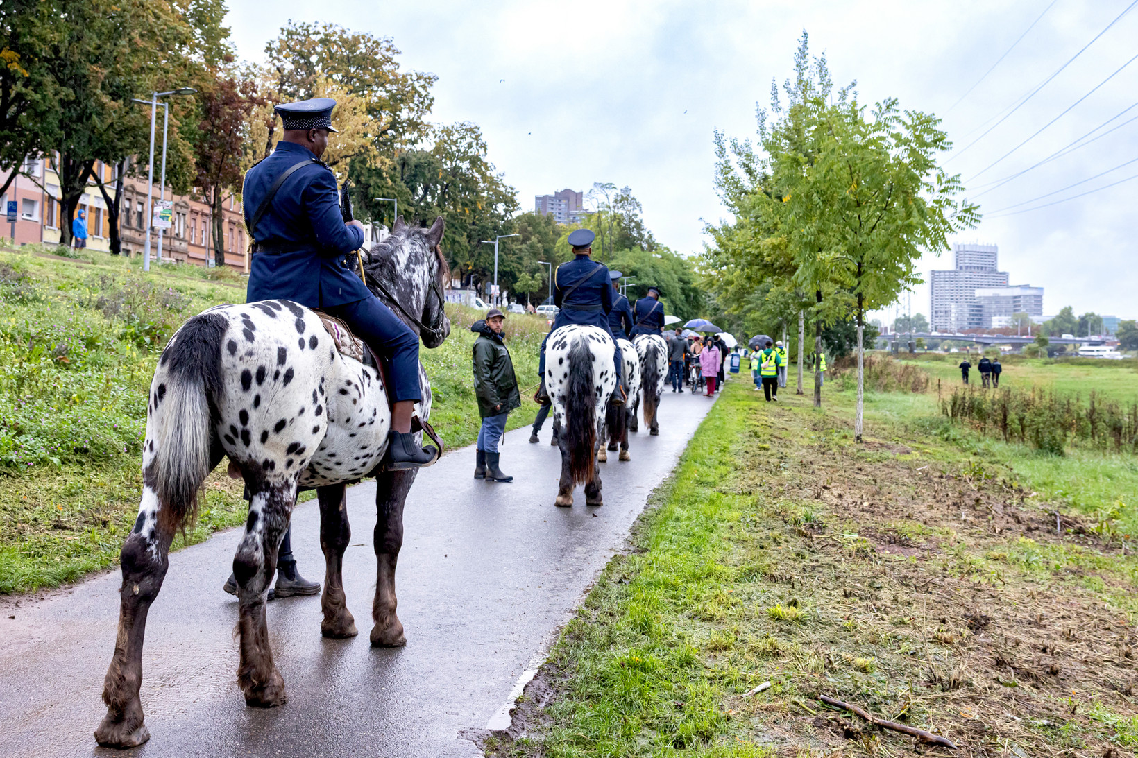 Vier Personen in Uniform reiten auf Pferden an der Neckarwiese entlang