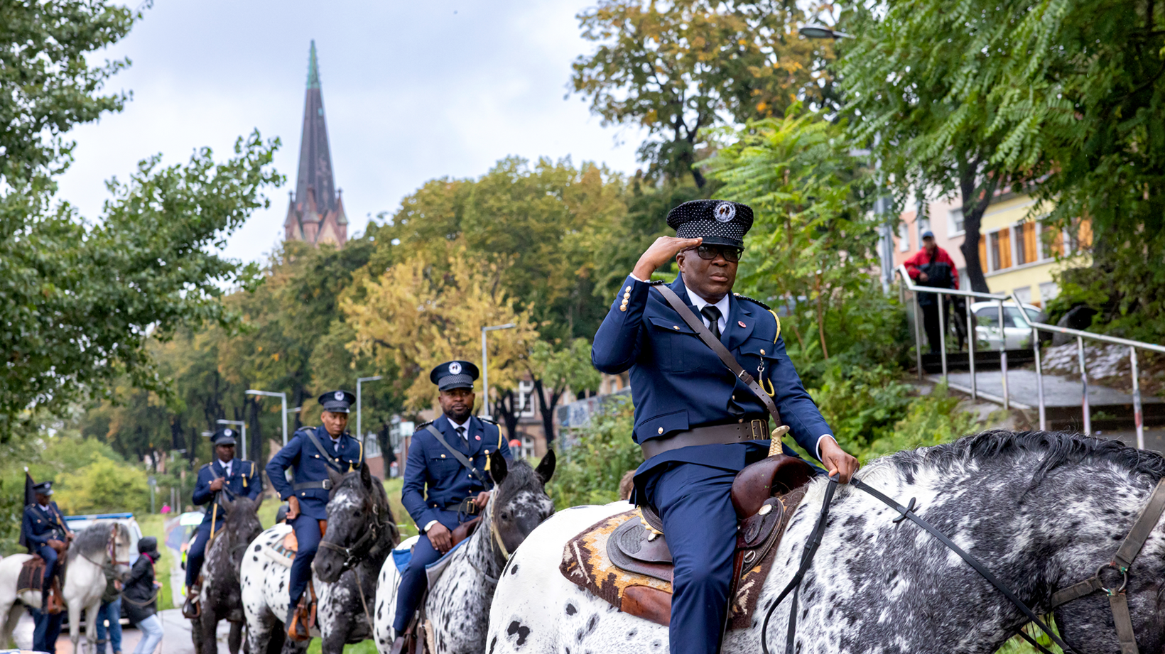 Personen in Militäruniformen reiten auf Pferden entlang der Neckarwiese