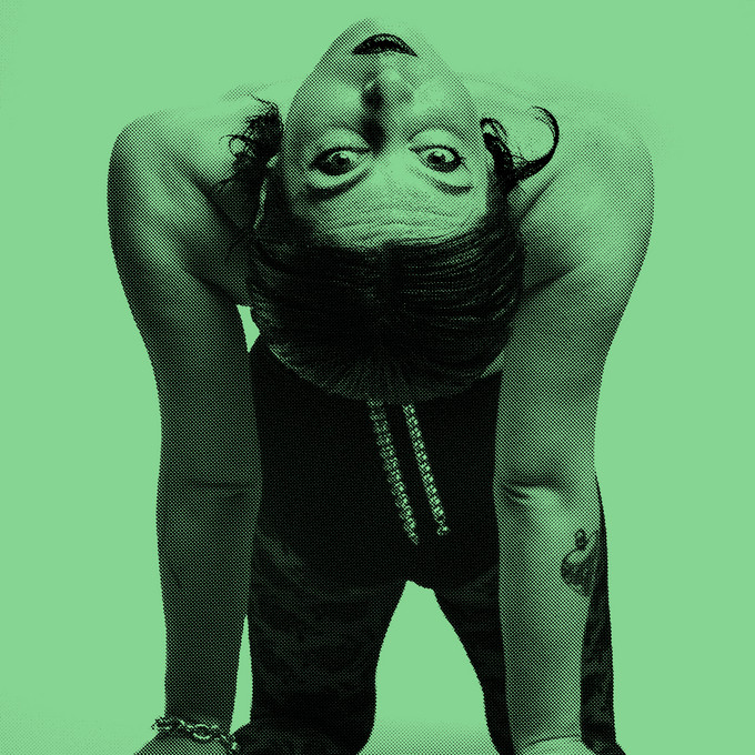 grün gefärbtes Bild. Eine Person sitzt mit dem Rücken zur Kamera, biegt sich aber so weit zurück, dass sie in die Kamera sehen kann.