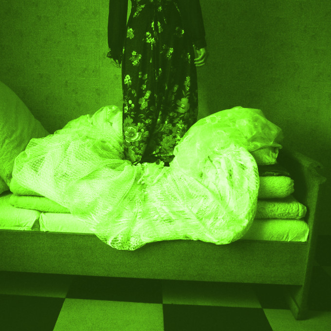 Person steht in einem Kleid auf einem Bett