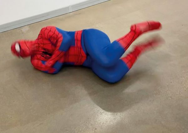 Träum unbedingt weiter Mann im Spiderman-Kostüm wälzt sich auf dem Boden. Das Bild ist unscharf.