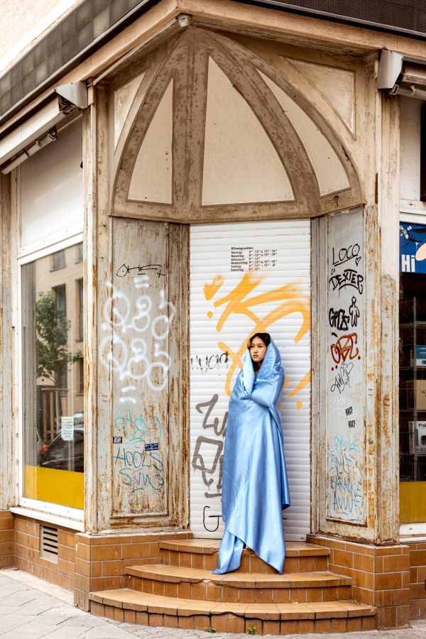 Yollar Frau im blauen Umhang steht in einem Hauseingang