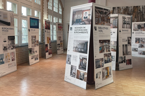 Ausstellung MOFA Ausstellungsraum mit zahlreichen Roll-Up Displays die unterschiedliche Bilder und Texte zu Innenarchitektur enthalten