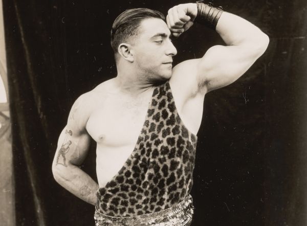 Männerphantasien Historisches sepiafarbenes Foto eines Mannes im Leopardenfell, der seinen Bizeps präsentiert