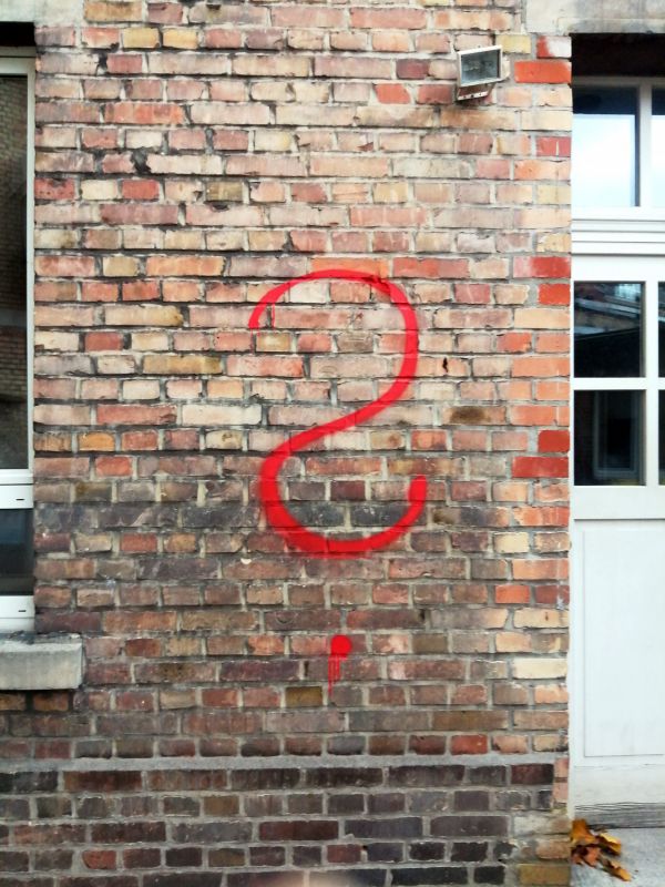 sneak peek alte Backsteinwand auf der in roter Farbe ein Fragezeichen gesprayt ist