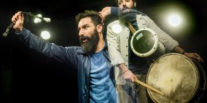 Mann tanzt mit Peitsche in der Hand, vor ihm ein Mann mit Trommel