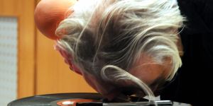 grauhaariger Mann liegt mit seiner Stirn auf einem Plattenspieler mit einer Schallplatte